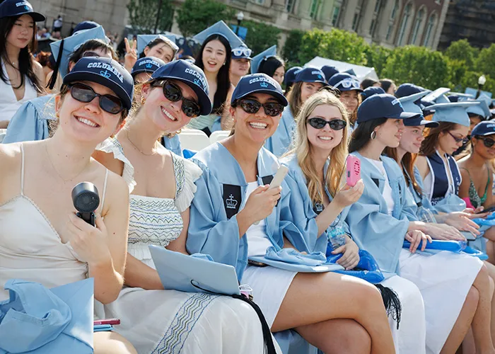 Columbia Commencement graduates with fans and hats.