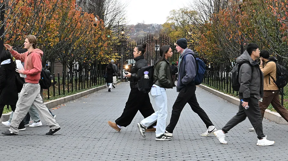 Students walking on Columbia’s Morningside campus with the closed gates in the background