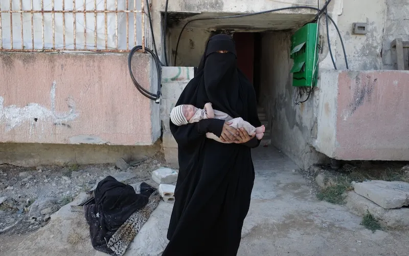 The wife of a Uyghur commander in Syria stands in front of their home. Photo by Emily Feng.