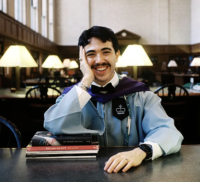 A Columbia 2025 grad poses in Butler Library’s reading room.
