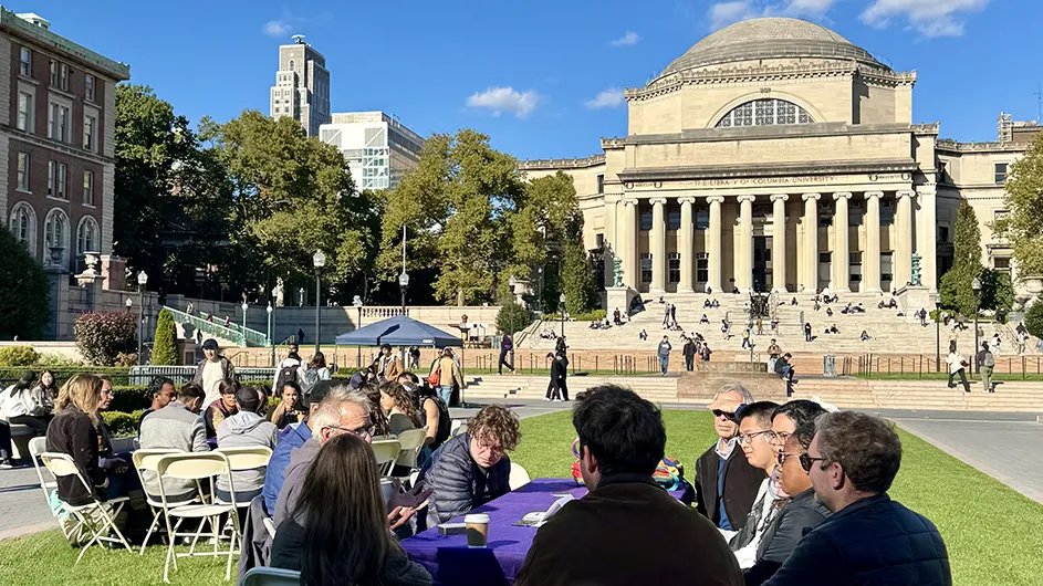 Groups of students, faculty, and staff talking around tables on Columbia’s Morningside campus. 