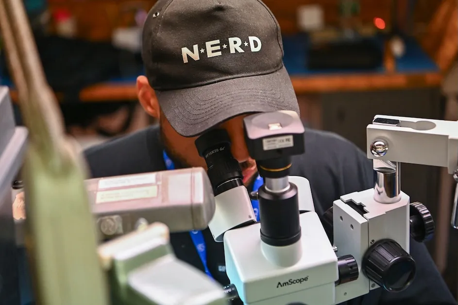 Electronics technician Luis Perez performs microscopically assisted soldering on a custom-designed electronics board that will eventually be sent to the Large Hadron Collider in Switzerland.