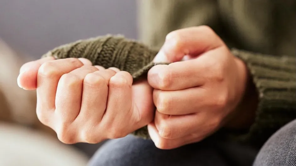 A person in a sweater clasping their hands.