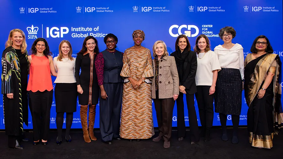 Eleven women (including Hillary Clinton, Sheryl Sandberg, Keren Yarhi-Milo, and Sierra Leone First Lady Bio) smile and pose on stage at a Columbia University Institute of Global Politics event.