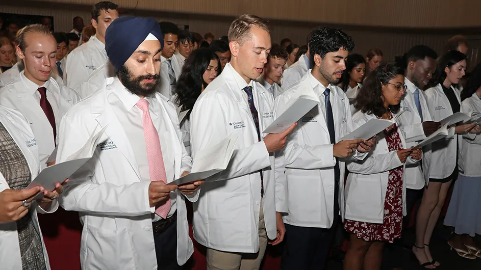 Several medical students in white coats recite the Hippocratic Oath at the Vagelos College of Physicians & Surgeons White Coat Ceremony at Columbia University Irving Medical Center