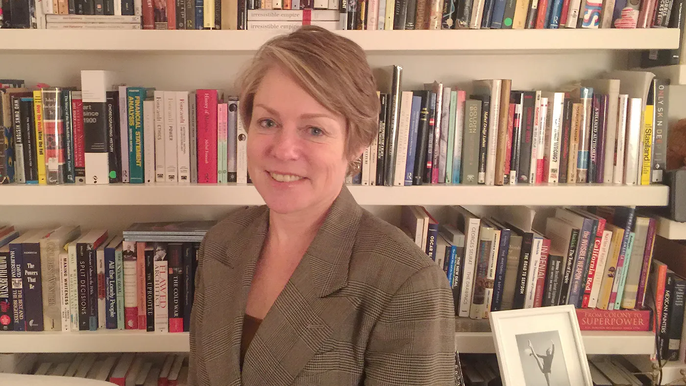 a woman smiling in front of a book case