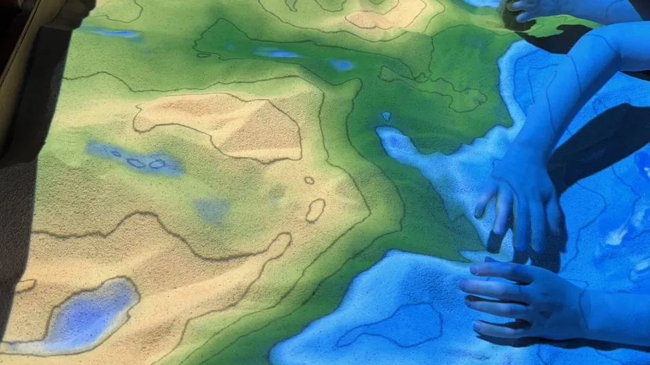 An augmented reality sandbox, where participants could help “map” the seafloor. Different colors represent different underwater depths. 
