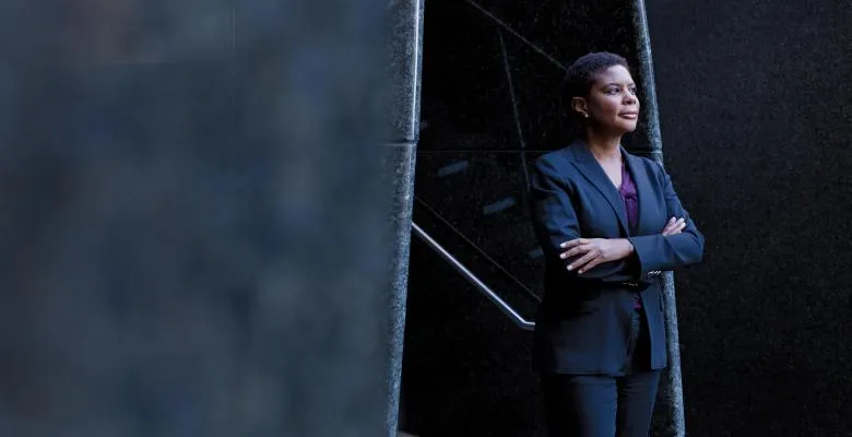 Image of Prof. Nelson in dark suit with purple blouse arms folded standing 