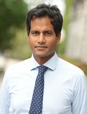 Jameer Jaffee dressed in light blue collared shirt with blue tie looking straight into camera 