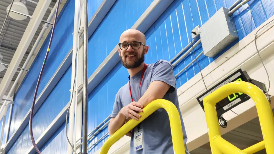 Jordan standing on a walkway at the National MagLab. 