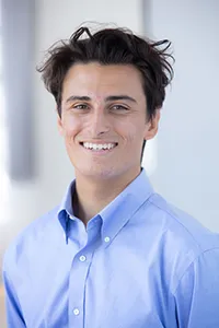young man with blue shirt and dark hair smiling