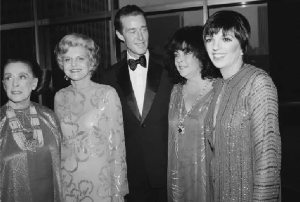 Four women and a man standing and posing for a photo