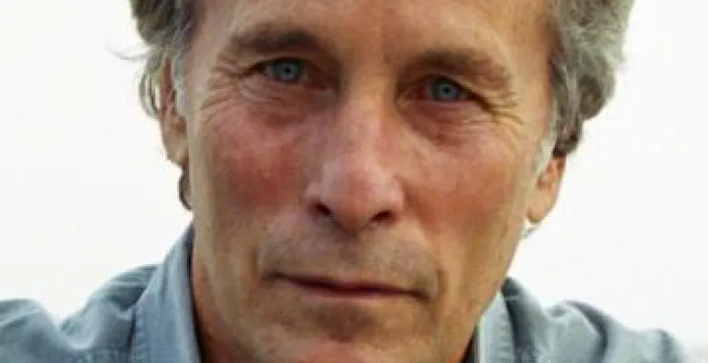 Man with gray hair and blue eyes squints at the camera