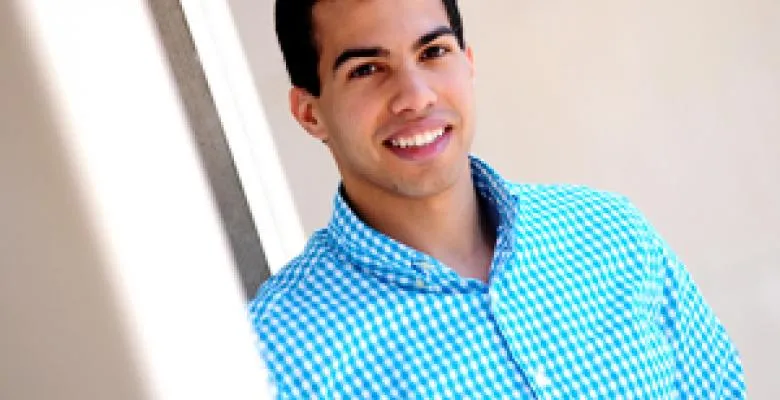 Young Columbia University graduate in a blue checkered shirt smiles at camera