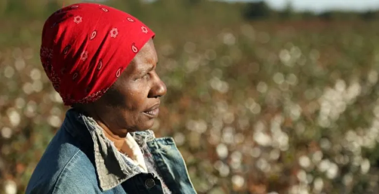 A woman with a red bandanna looks off in the distance