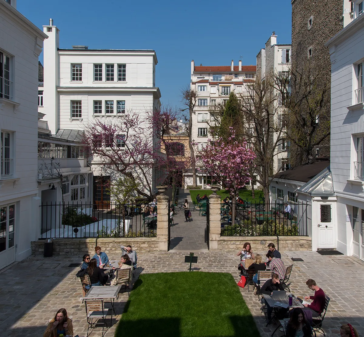 Photo of the courtyard and garden at Reid Hall, surrounded by white stone buildings