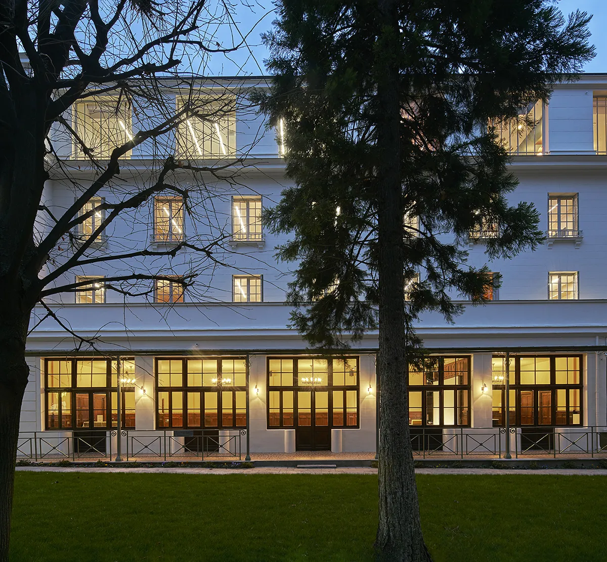 Photograph of the front of a white stone building at dusk
