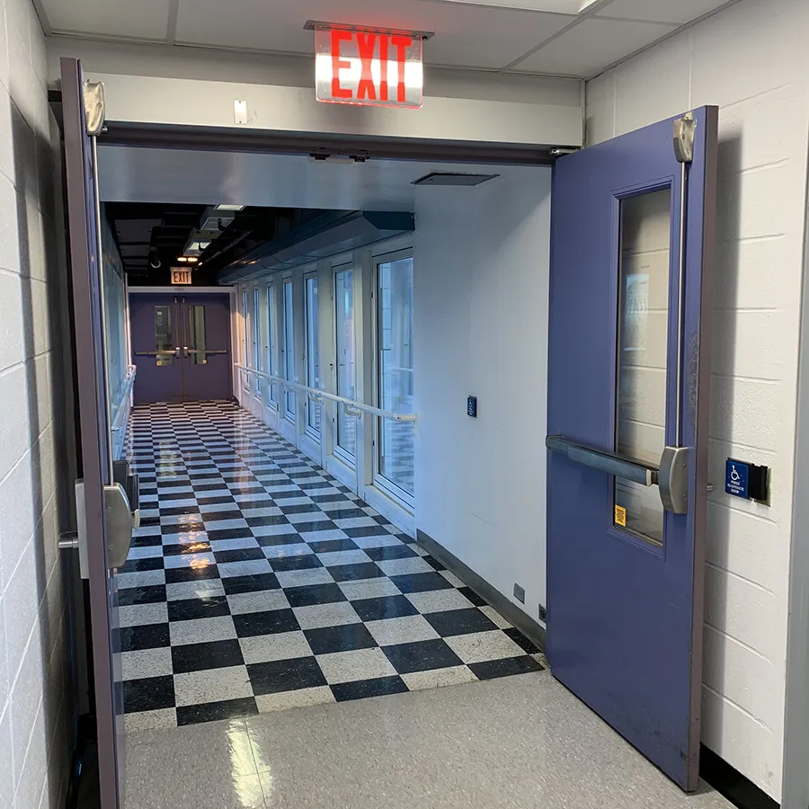 In the Pupin Hall building, a button on the wall of a checkered-floor hallway open sky bridge doors.