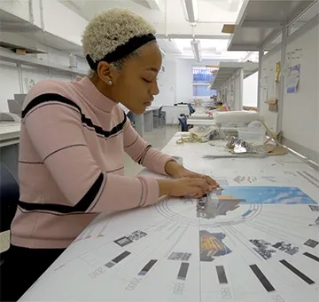 Cecley Hill sits at a desk working on her print designs.