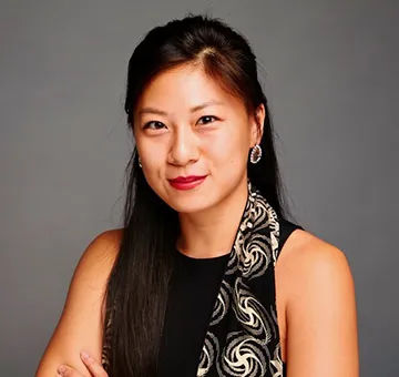 Sun Ming Jessica Pan in a black dress and scarf in front of a gray backdrop.