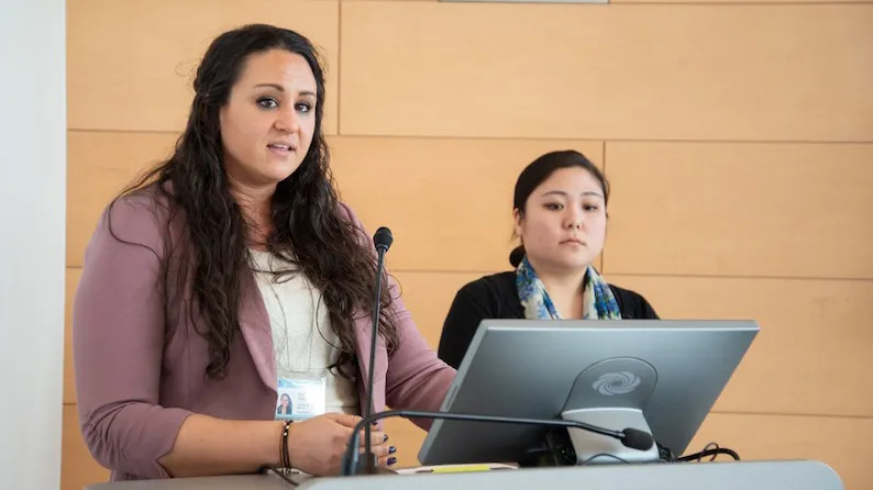 Two of the Columbia University senate stand at a podium with a microphone. 