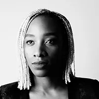 Headshot of Karimah Ashadu, a dark-skinned woman with light braids in a black top