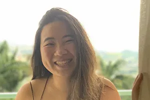 Alice Fang: A smiling woman, who is a Columbia student based in Brazil, against a green tropical backdrop.