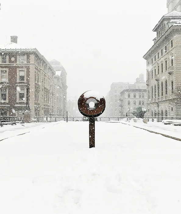 A circular statue stands overlooking Morningside campus on Revson Plaza.