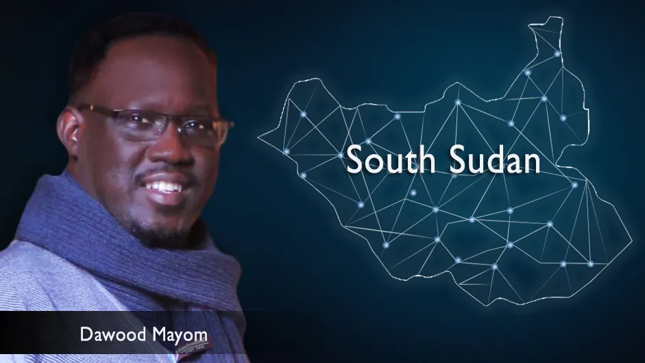 A man with short hair and glasses, in a blue scarf and shirt, against the backdrop of an astral map of South Sudan.