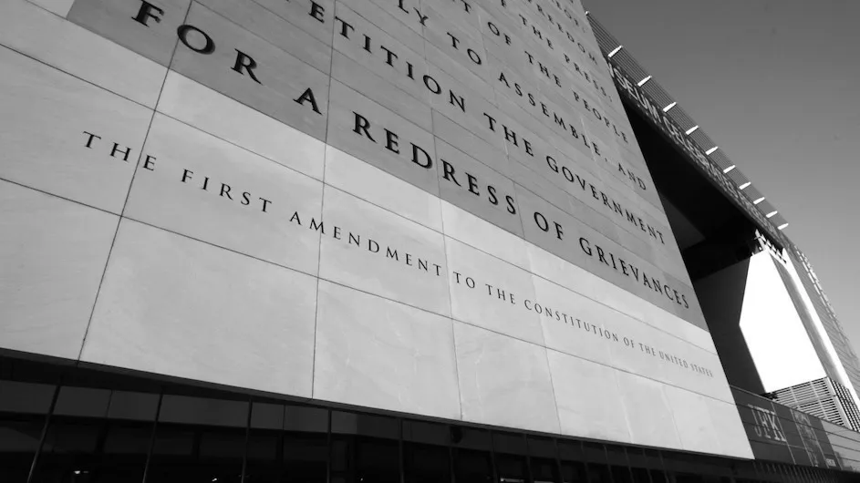 A black and white photo of a side a building with the First Amendment inscribed on it.