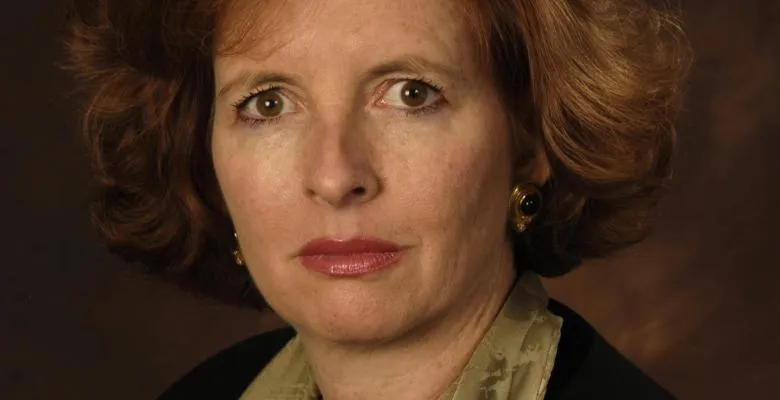 A red-haired business woman stares intently at the camera