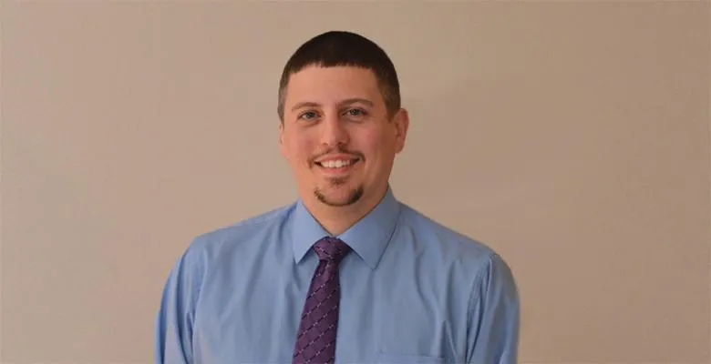 Richard Nephew in a light blue button-down shirt and purple tie