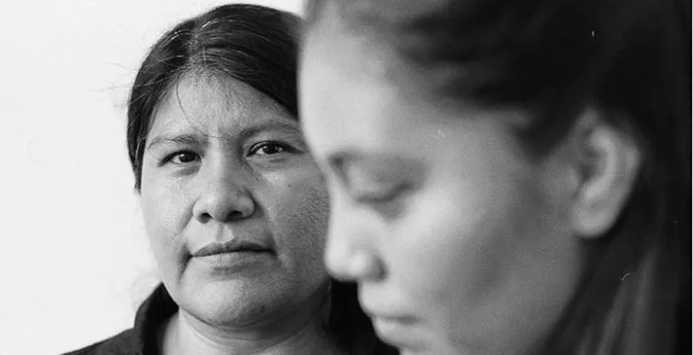 A woman looks directly at the camera in a black and white photo.