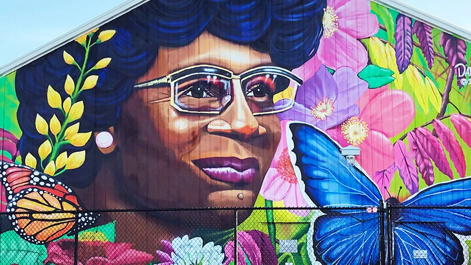 A colorful mural of Shirley Chisholm with flowers and butterflies around her face. 