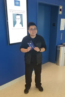 Justin Tsui, young man with black hair and glasses, holding a blue pouch
