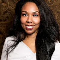 African-American woman with long black hair smiling, white dress