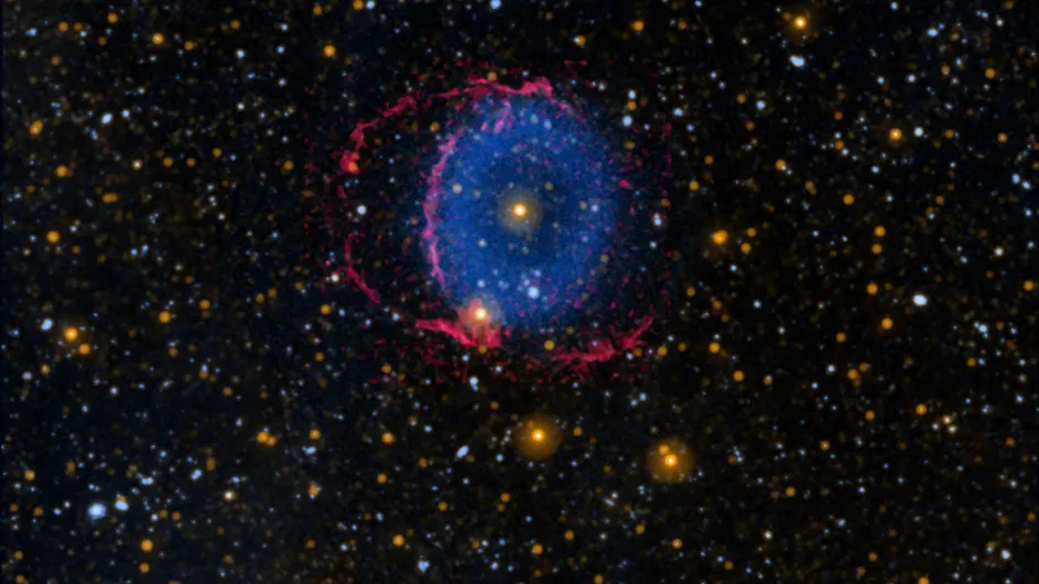 Black sky with hundreds of small stars and at center a blue donut-shaped ring with red lines surrounding it