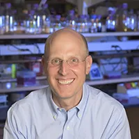 Headshot of Columbia Trustee Jonathan Rosand: Man with wire glasses in a light blue collared shirt.