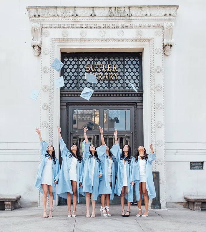 A group of grads throws their grad caps in front of Butler Library.