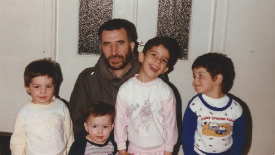 Four children pose around an adult male for a photo.