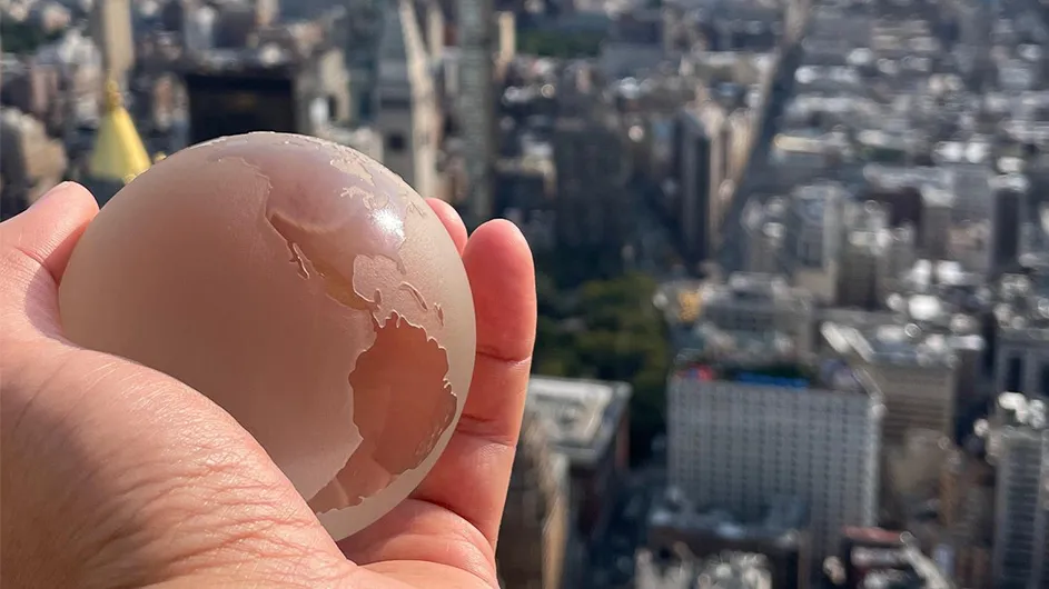 A globe in a hand over a city.