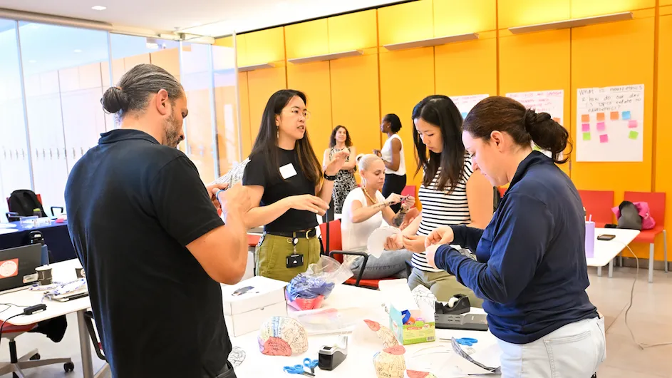 Diana Li, PhD, (center left) associate director of education and training initiatives at the Zuckerman Institute, mingles with Neuroethics Teacher Institute attendees Tim Carlin (left), Jenny Palumbo (striped shirt) and Brianna DeSantis during a lesson-planning workshop. (Credit: Diane Bondareff/Columbia’s Zuckerman Institute)